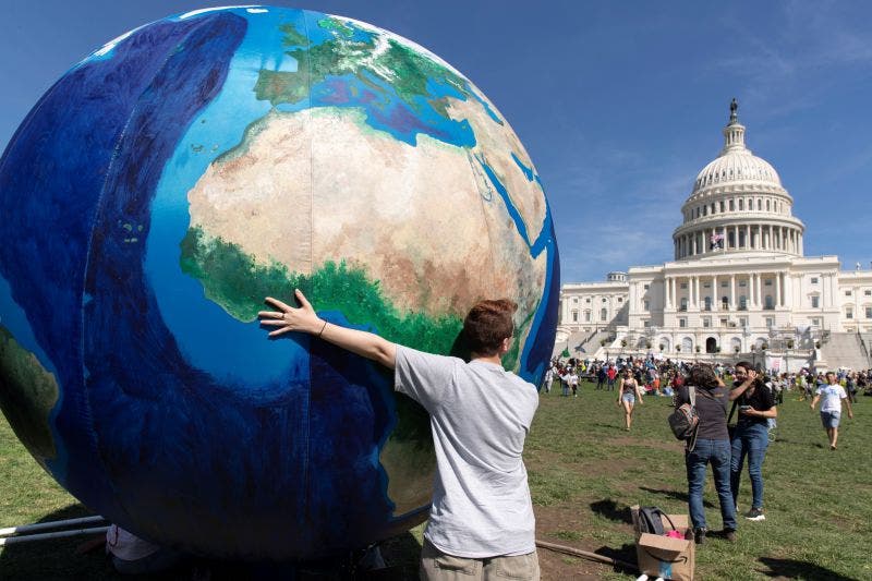 Un joven se abraza a un balón inflable, que representa al planeta frente al Capitolio en Washington, Estados Unidos.