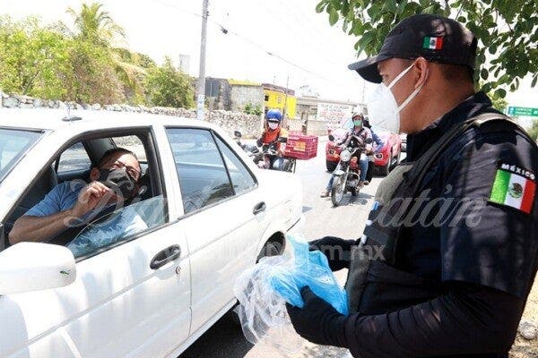 Policías repartiendo cubrebocas en los filtros.- Foto: Diario de Yucatán