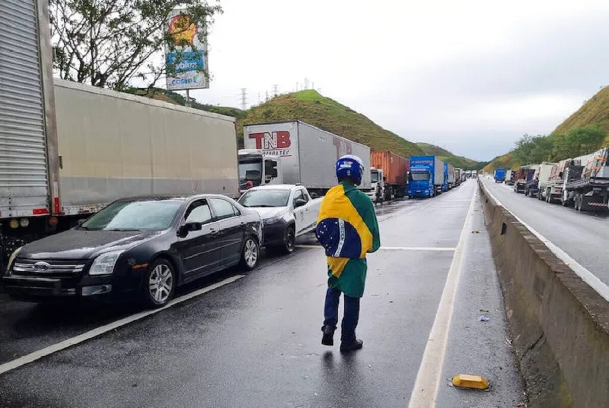 Un camionero con una bandera brasileña camina junto a camiones de carga detenidos en la carretera entre Río de Janeiro y Sao Paulo para protestar por la derrota electoral el día anterior del Presidente Jair Bolsonaro, el lunes 31 de octubre de 2022, en Barra Mansa, estado de Río de Janeiro, Brasil. Foto: Rodrigues Da Silva, AP