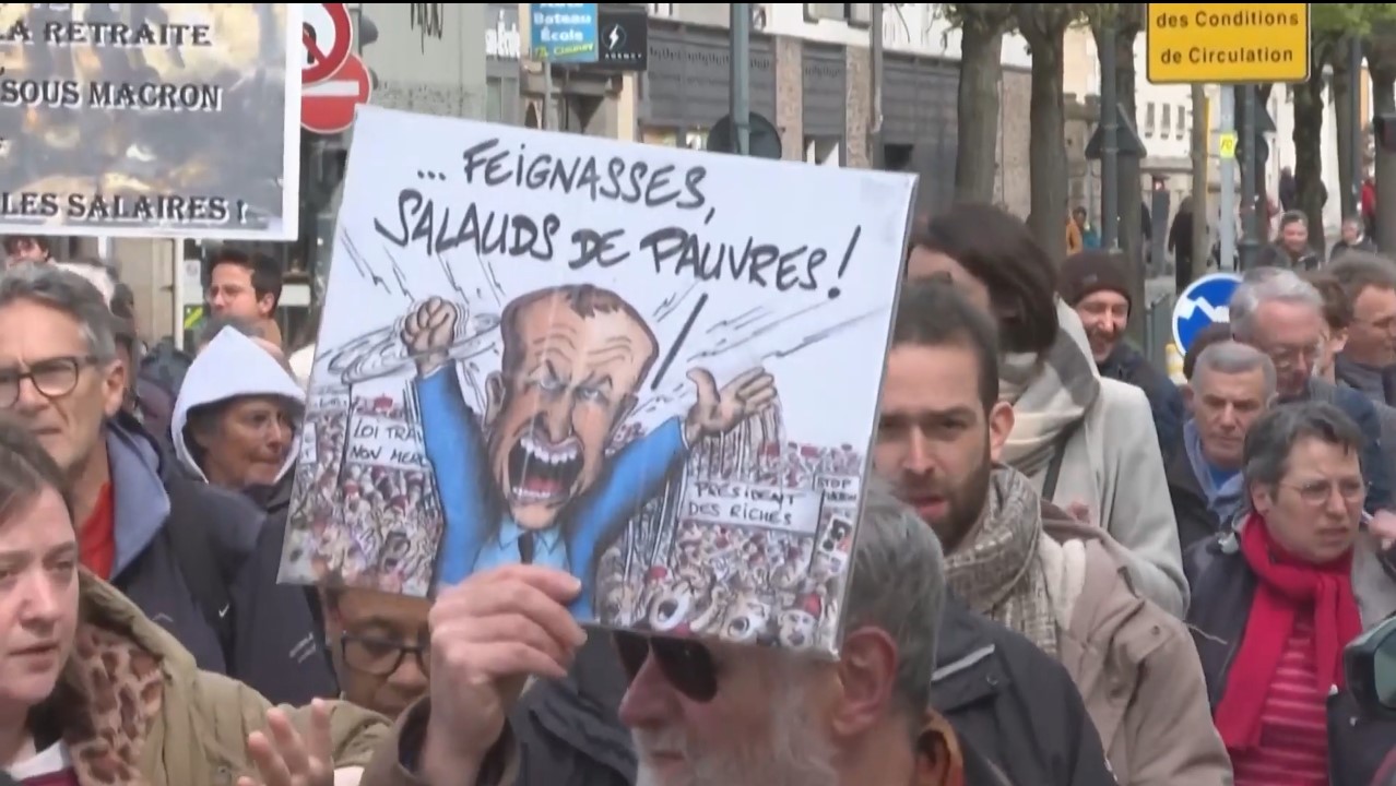 Crece el encono y la molestia del pueblo francés en contra de su presidente Emmanuel Macron por la reforma al régimen de pensiones; una persona porta un catel en el que se ve la figura del mandatario galo vociferando: "...perezosos, pobres bastardos!"