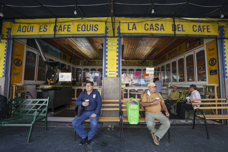 Personas beben café en una banca frente al Café Equis en el marco del Día Internacional del Café, en la Ciudad de México, capital de México, el 1 de octubre de 2021. (Xinhua/Luis Licona)