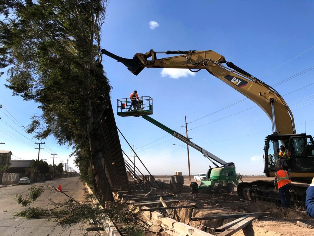 Una grúa intenta sostener trozos del muro fronterizo que cayeron en la frontera de Calexico, California en 2020.