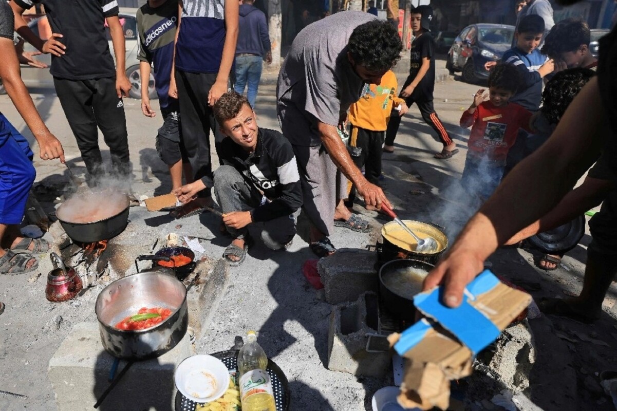 Palestinos desplazados preparan comida frente a una escuela de la Agencia de la ONU para los refugiados palestinos, en un campamento en la franja de Gaza, el 7 de noviembre de 2023.