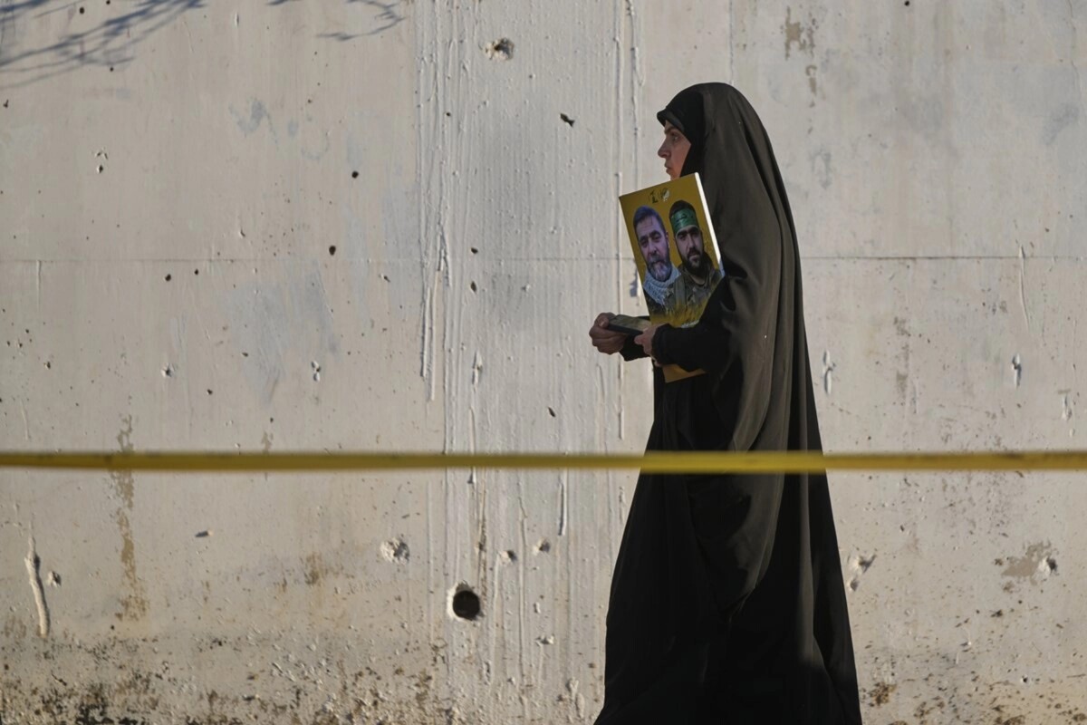 En la ciudad libanesa de Tiro, devastada por el ejército israelí, una mujer porta un cartel con combatientes de Hezbollah, en el tercer día de la festividad religiosa de la Ashura.