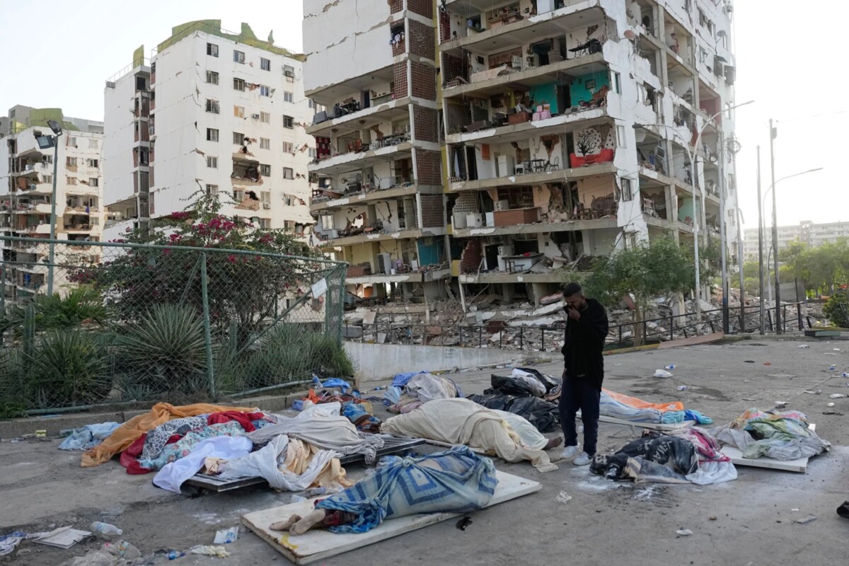 Un hombre observa cuerpos cubiertos mientras busca a familiares desaparecidos tres días después de que los terremotos azotaran Catia La Mar, Venezuela, el sábado 27 de junio de 2026.  