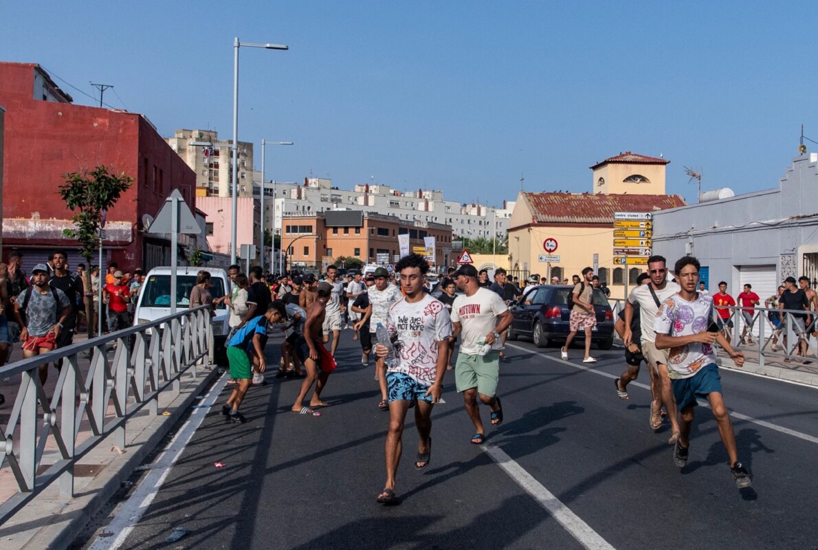 Migrantes huyen de policías españoles el viernes 31 de julio de 2026 tras cruzar desde Marruecos al enclave español de Ceuta.  